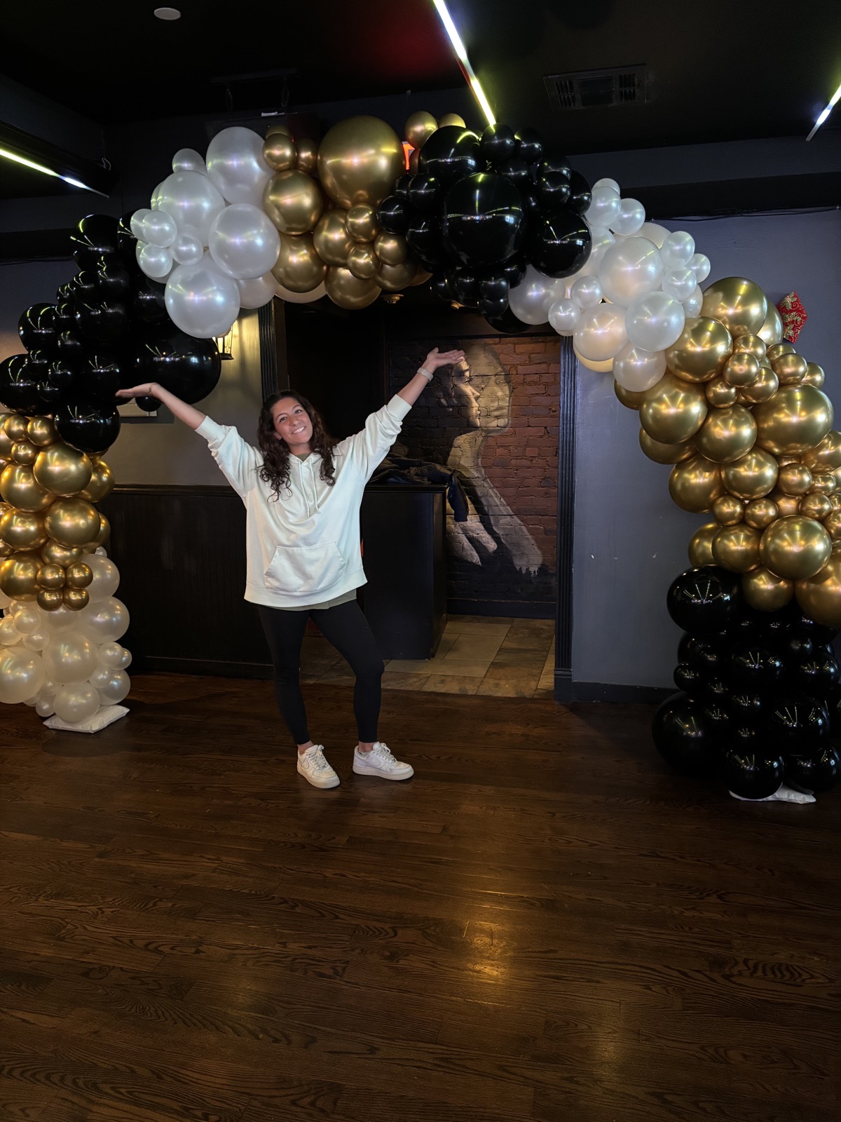 Lisa in front of a black and gold balloon arch